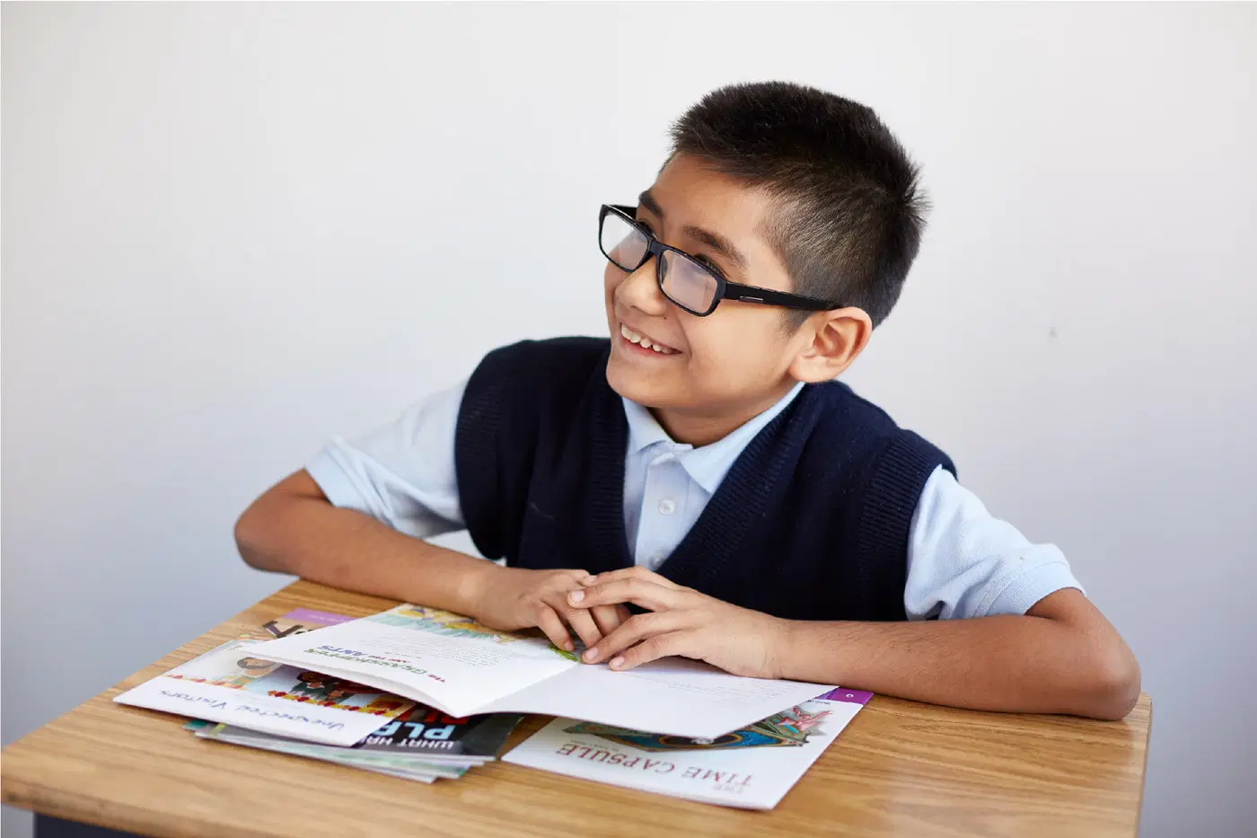 male student smiling with books at desk