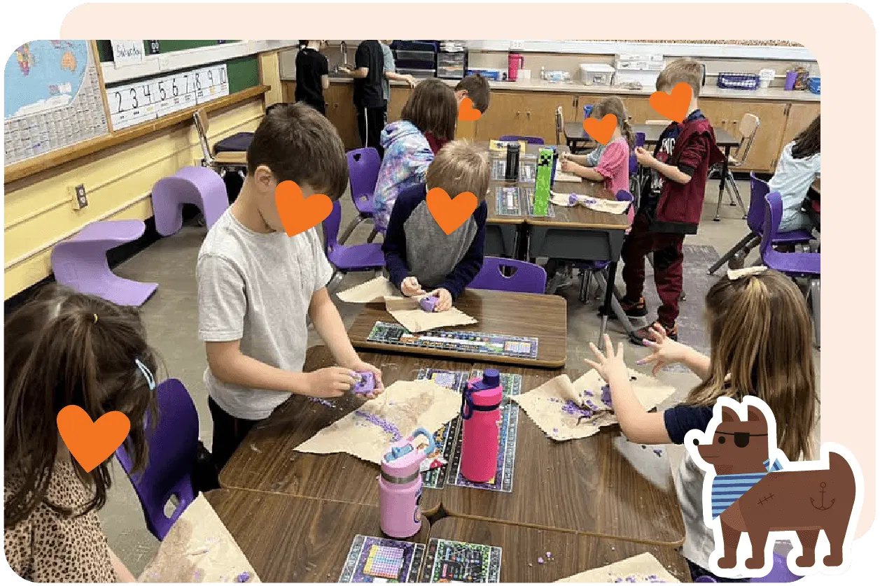 Children in a classroom are engaged in a hands-on activity, creating crafts at desks. Various supplies and water bottles are on the tables.