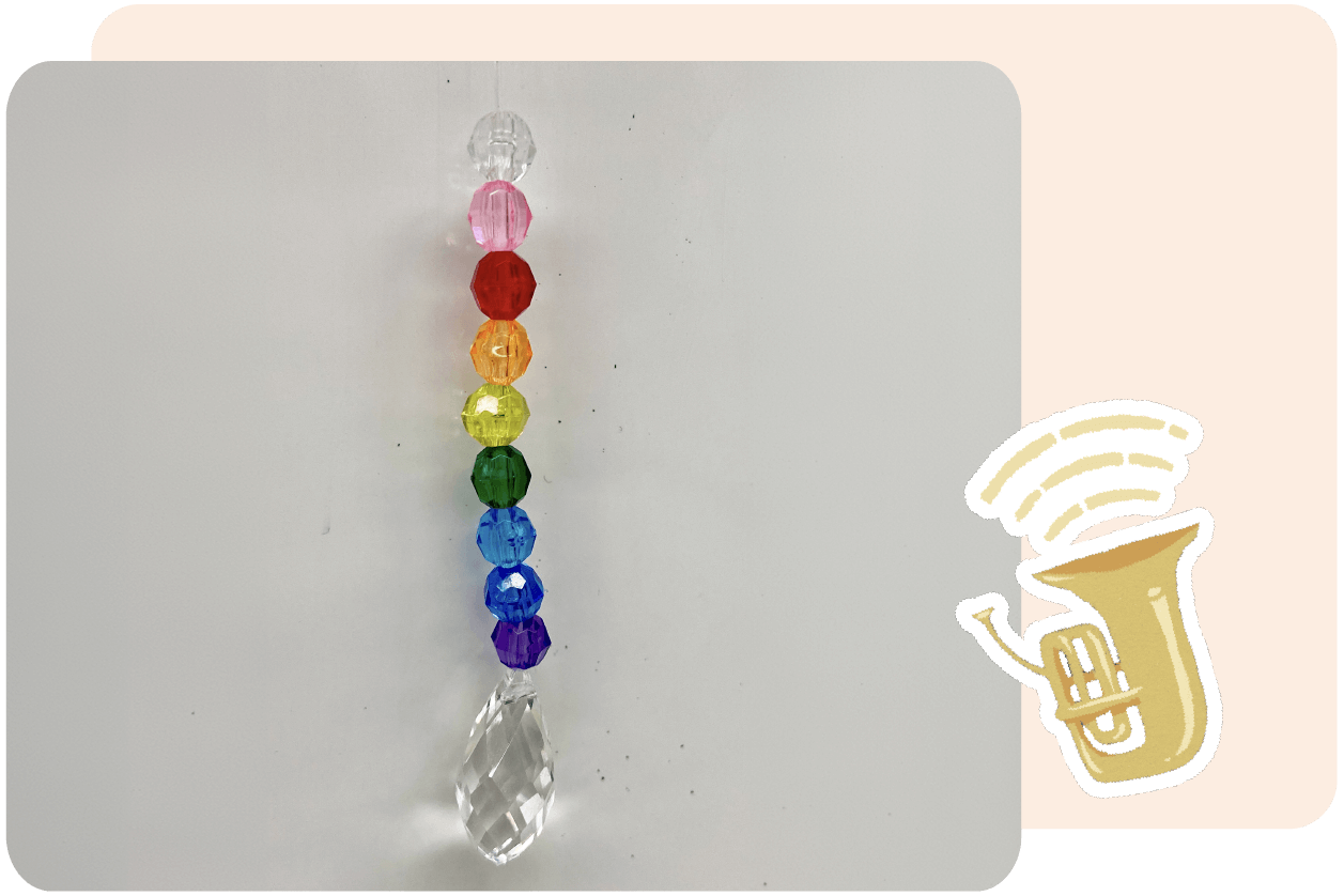 Hanging crystal prism with beads in rainbow colors alongside a cartoon tuba with sound waves.