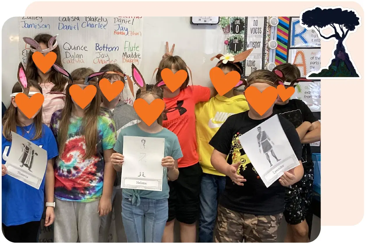 A group of children stand together in front of a classroom whiteboard, holding various printed images. Their faces are covered with orange heart shapes.