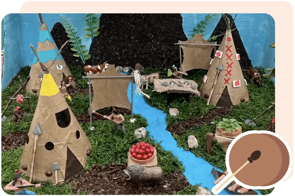A diorama depicting a Native American village with tipis, a stream, figures of people, animals, and items like a basket of tomatoes, set against a background of trees and mountains.