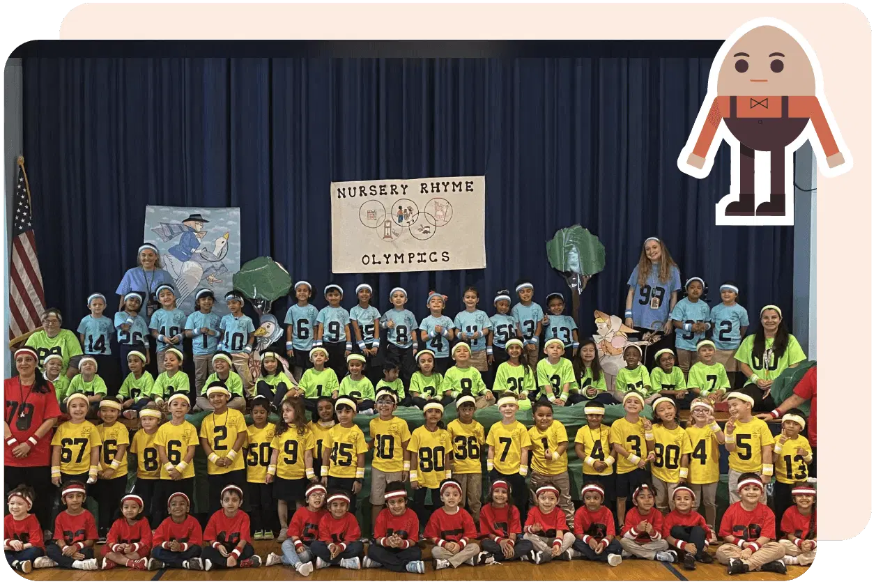 A large group of children wearing colorful sports jersey costumes stand on a stage labeled "Nursery Rhyme Olympics," with drawings of nursery rhyme characters in the background.