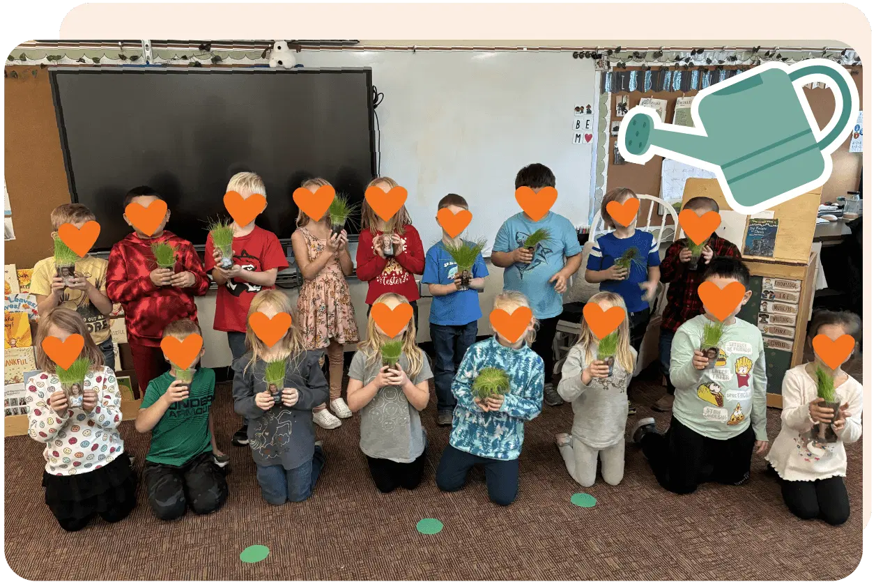 A group of children holds small plants in a classroom, posing for a photo. Their faces are obscured by heart icons. A watering can graphic is in the top right corner.