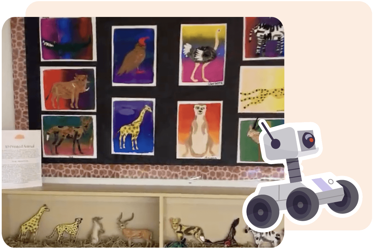 Bulletin board displaying colorful animal artwork, including birds, giraffes, and a meerkat. Below the board are animal figurines and an informational sign. There is a cartoon robot graphic on the right.
