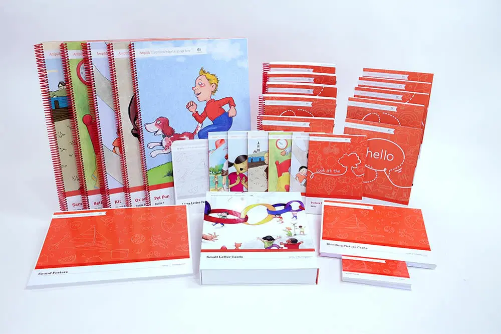 A collection of educational books, workbooks, flashcards, and teaching materials with red and white covers displayed on a white background.