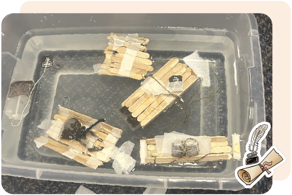 Four small homemade rafts made of popsicle sticks and tape float in a clear plastic container filled with water—an engaging hands-on project and a great addition to resources for teachers seeking creative STEM activities.