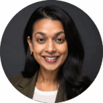 A woman with long dark hair, wearing a blazer and white top, smiles at the camera against a dark background, embodying confidence and expertise in the science of reading.