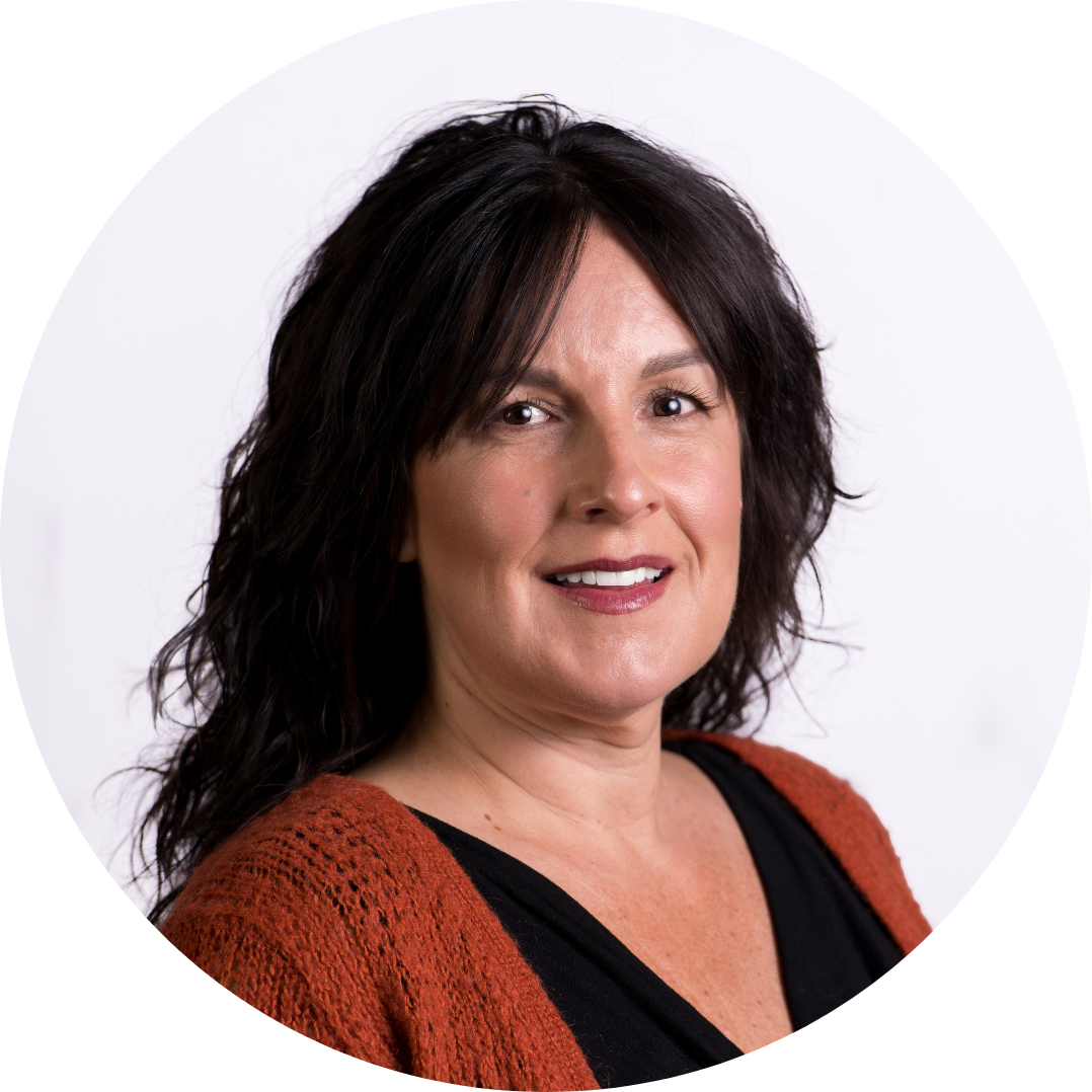 Middle-aged woman with shoulder-length dark hair, wearing a black top and orange cardigan, smiling against a white background.