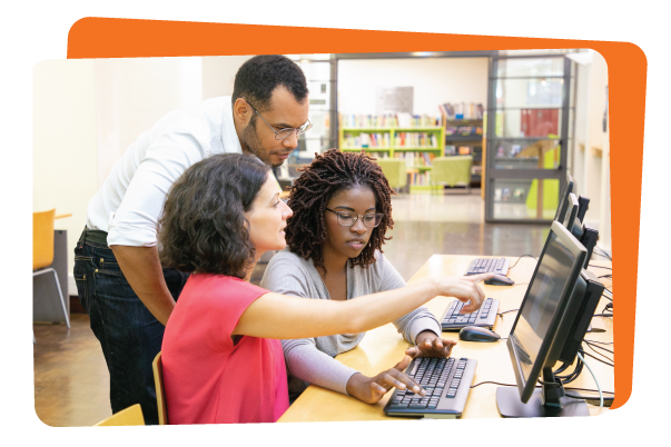 Three adults, two women and one man, engage in professional development for teachers using computers in a library setting.
