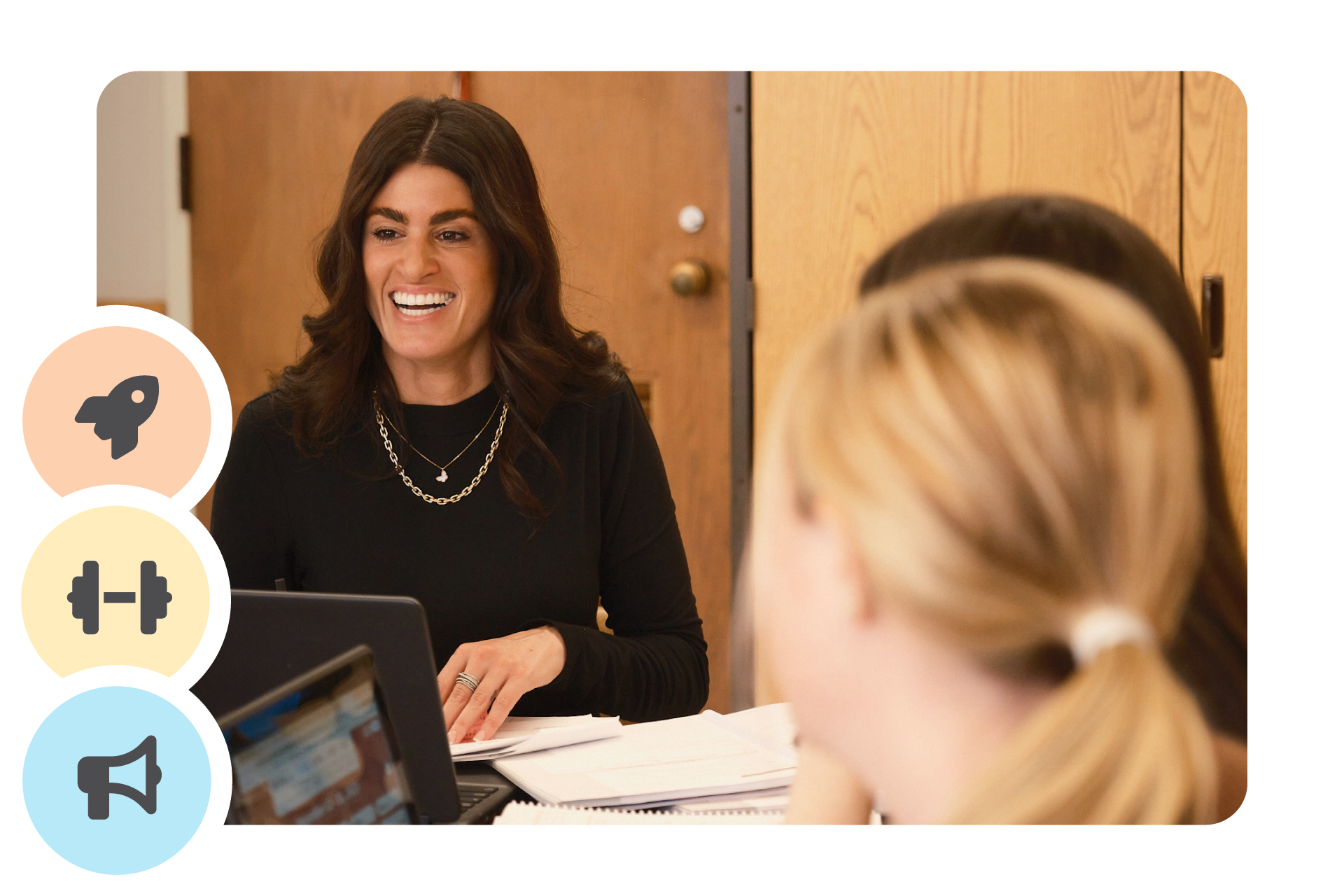 A woman with long dark hair smiles while sitting at a table with two others, papers and laptops in front of them. Three circular icons are displayed on the left side.